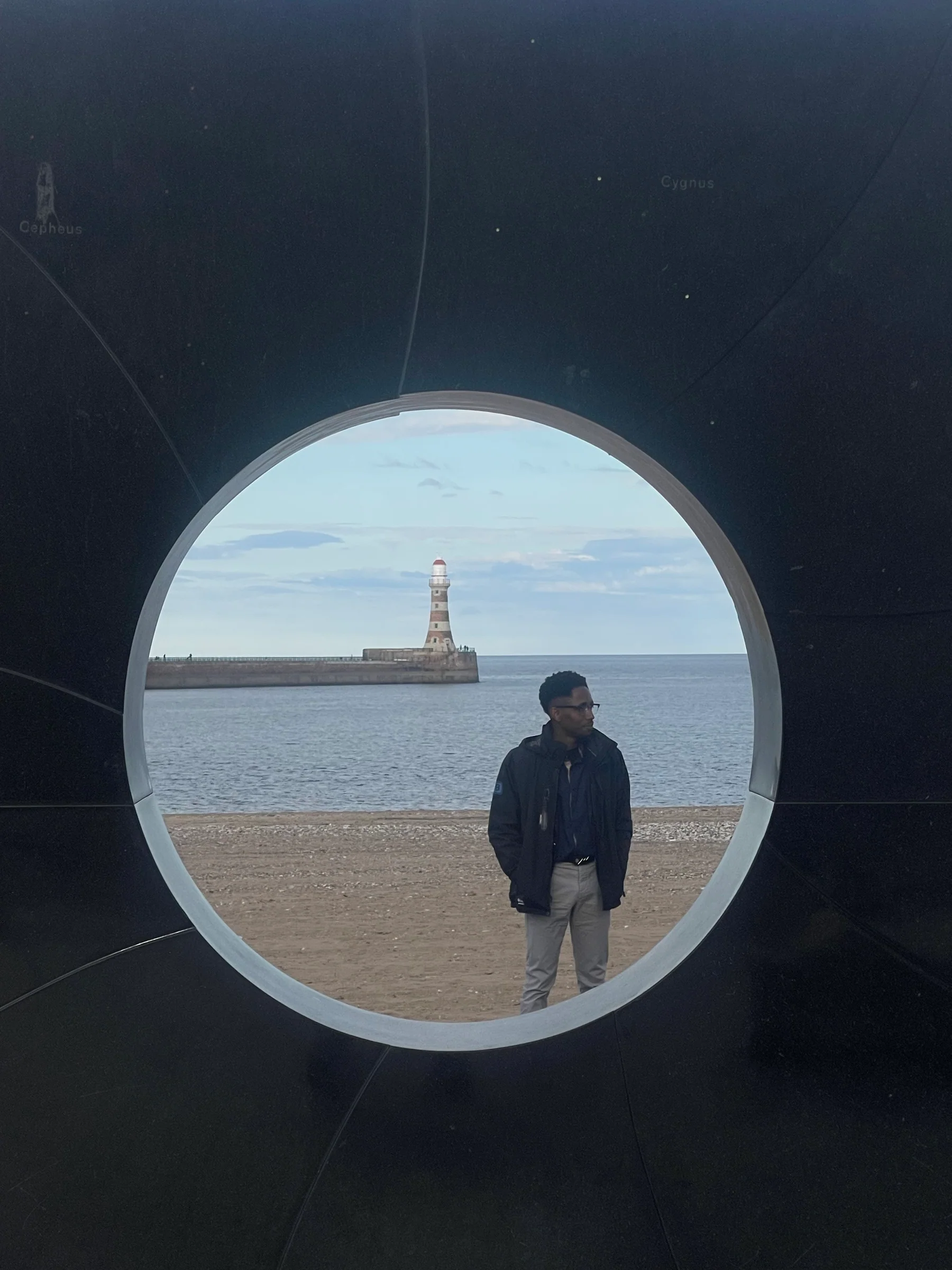 Kufre Antia photographed through an architectural opening with Roker Lighthouse beyond