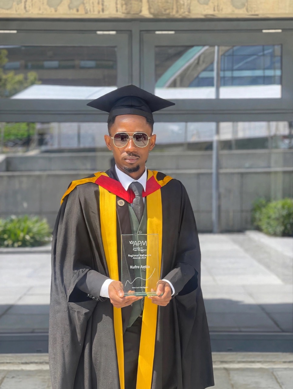 Kufre Usen Antia in graduation attire holding his APM North East Student of the Year award